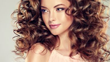 Beautiful model girl with wavy hairstyle . Brunette woman with long curly hair
